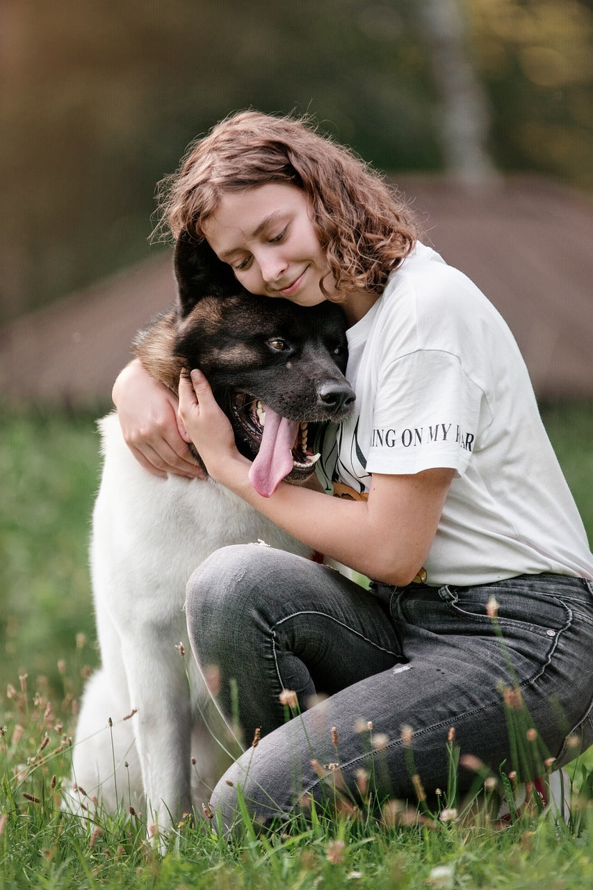 girl kneeling cuddling brown and white dog